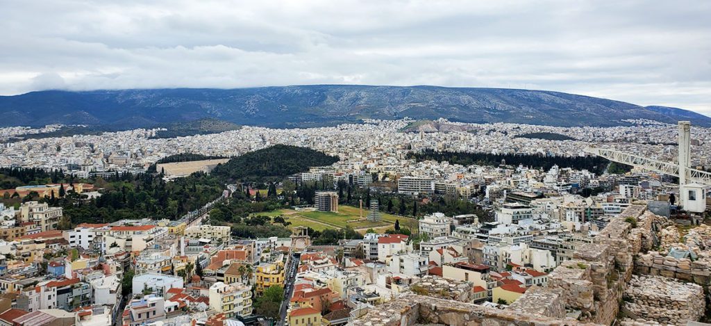 This is an image of a city view of Athens at Acropolis with mountain views and greenery. 