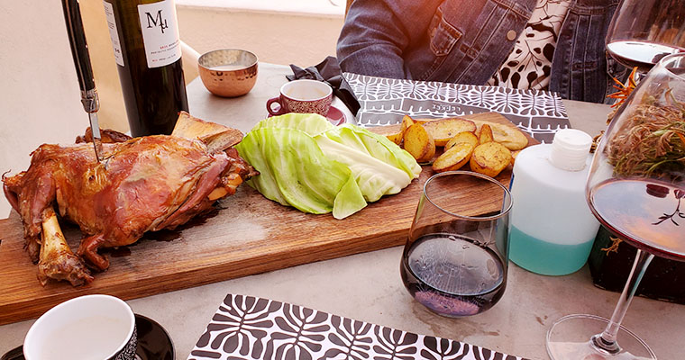 This is an image of the Lamb for two at Lefkes, a restaurant in Finikia with leeks and roasted potatoes, paired with a local wine. Traveling and food in Greece.