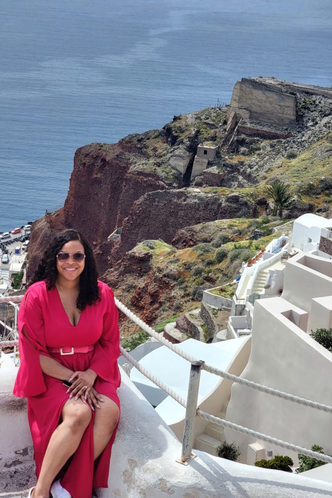 This is an image of T sitting on a rail in Oia overlooking the sea.