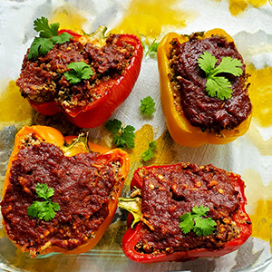 This is an image of the stuffed bell peppers. The peppers are cut in half, stuffed, and topped with a sweet and spicy tomato-based sauce.