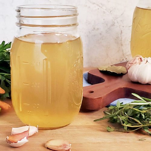 This is an image of the vegetable broth. The image is decorated with fresh vegetables and herbs.