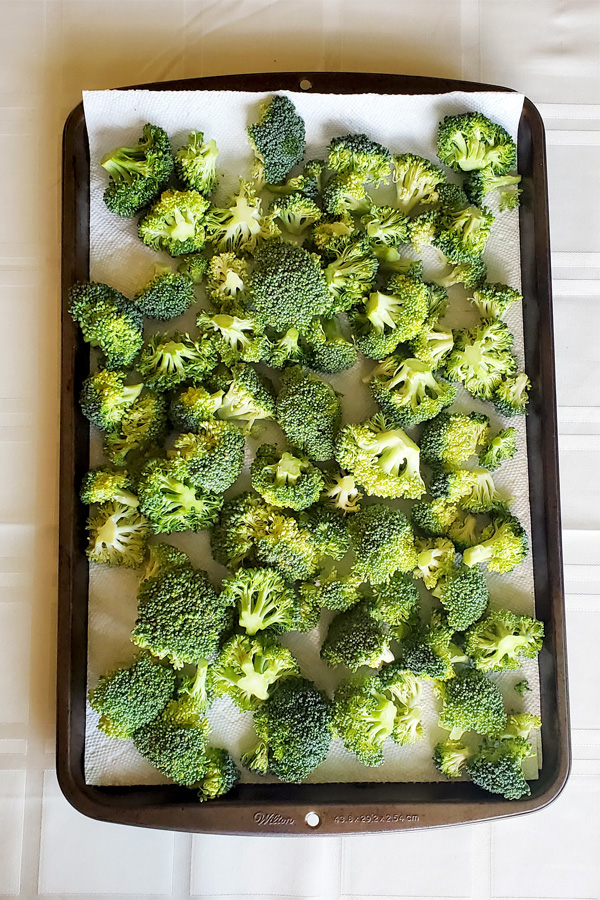 This is an image of broccoli fleurettes on a cookie sheet with paper towels for drying.