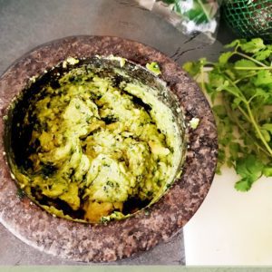 This is an image of the best guacamole recipe, staged with cilantro, avocado, and jalapeno peppers.