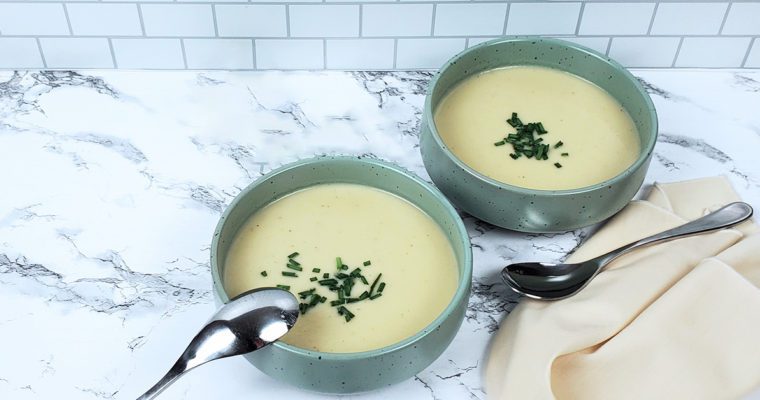 This is an image of two bowls with the potato leek soup garnished with fresh chives.