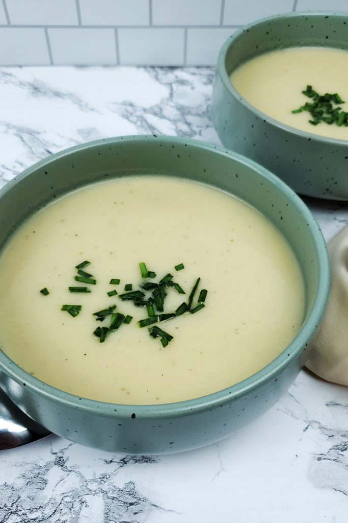 This is an image of two bowls with the potato leek soup garnished with fresh chives.