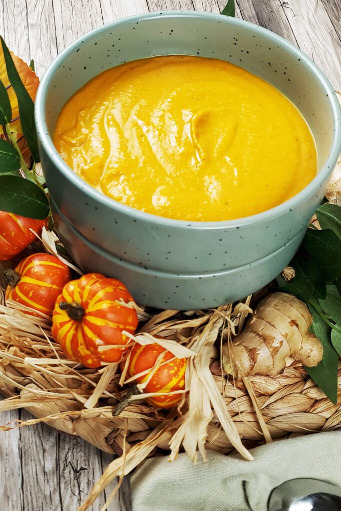 This is an image of the carrot ginger soup decorated with a pumpkin wreath and fresh ginger.