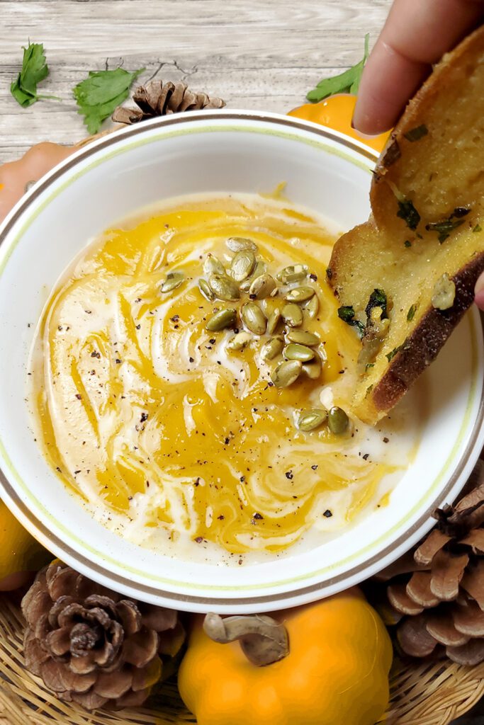 This is an image of Sundays at T's butternut squash bisque with the garlic confit toast. The bisque is garnished with coconut cream, pepitas, and cracked black pepper.