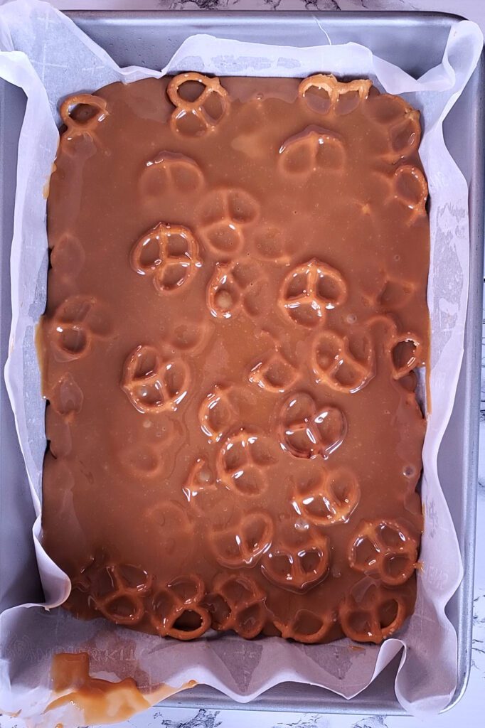 This is an image of melted caramel on top of the layer of pretzels for the copycat take5 for Sundays at T's