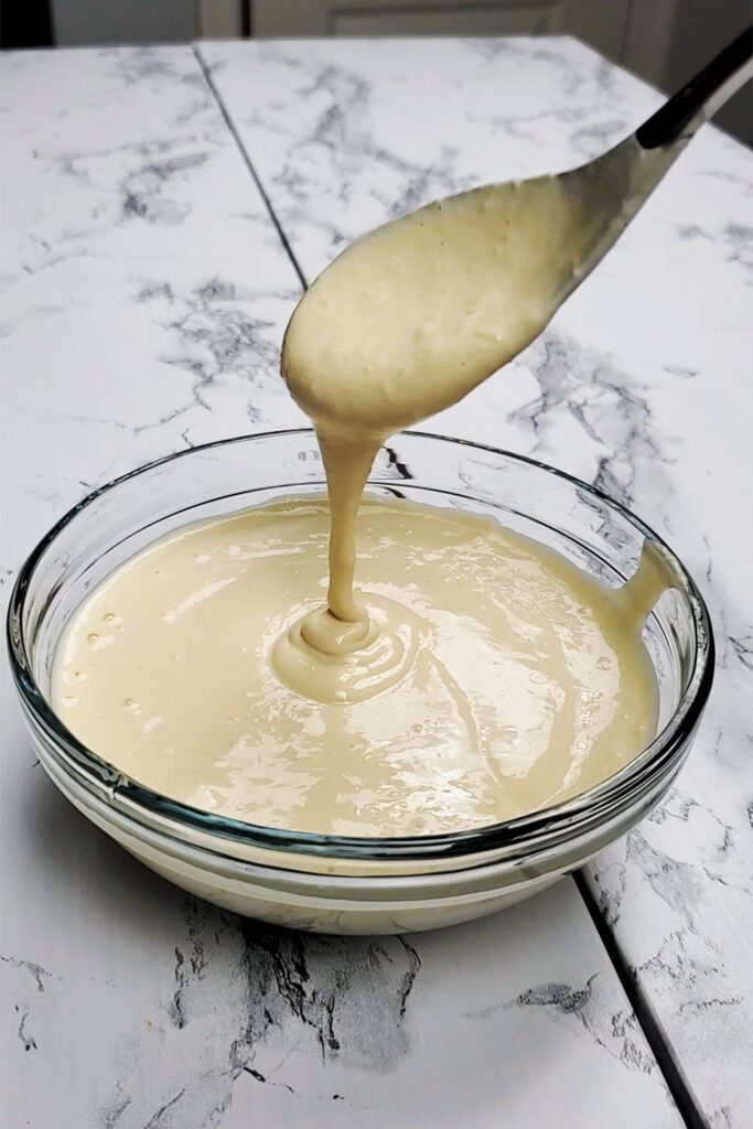 This is an image showing the creamy texture of the tahini dressing in a clear bowl with a spoon.