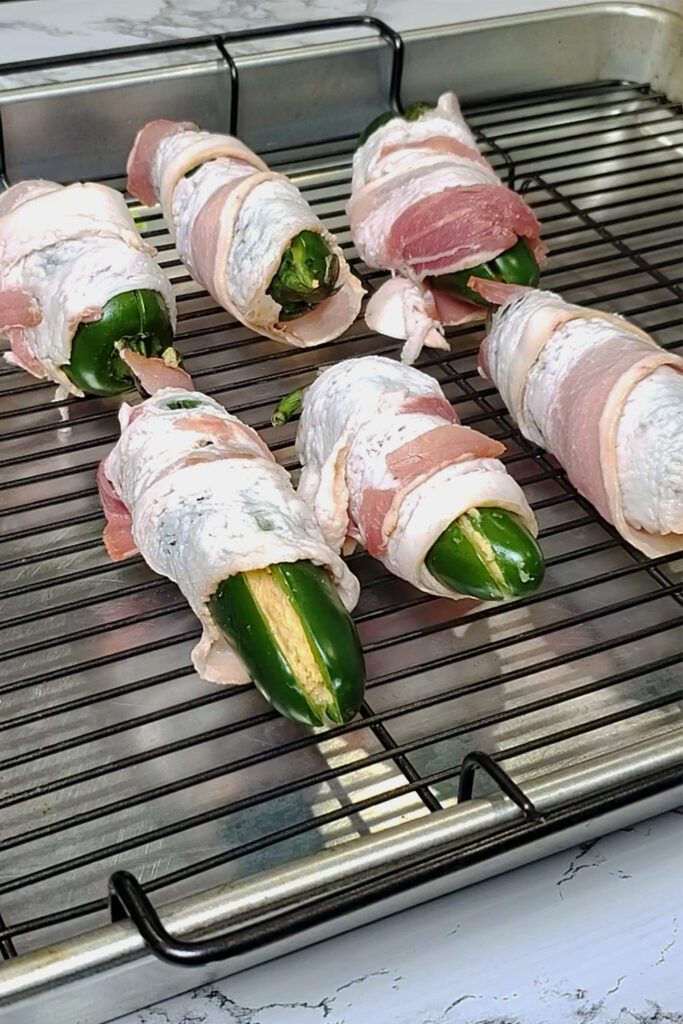 This is an image of stuffed bacon jalapenos from Sundays at T's before baking. These jalapeno poppers are stuffed with three cheeses (cream cheese, pepper jack cheese, and cheddar cheese), paprika, and garlic.