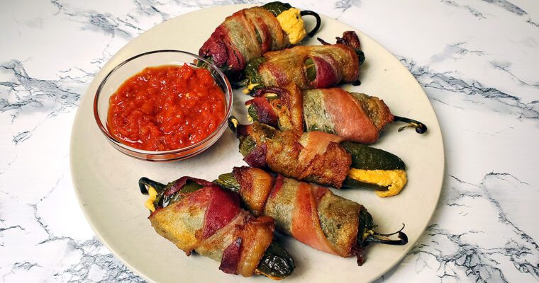 This is an image of stuffed bacon jalapenos from Sundays at T's. These jalapeno poppers are stuffed with three cheeses (cream cheese, pepper jack cheese, and cheddar cheese), paprika, and garlic.