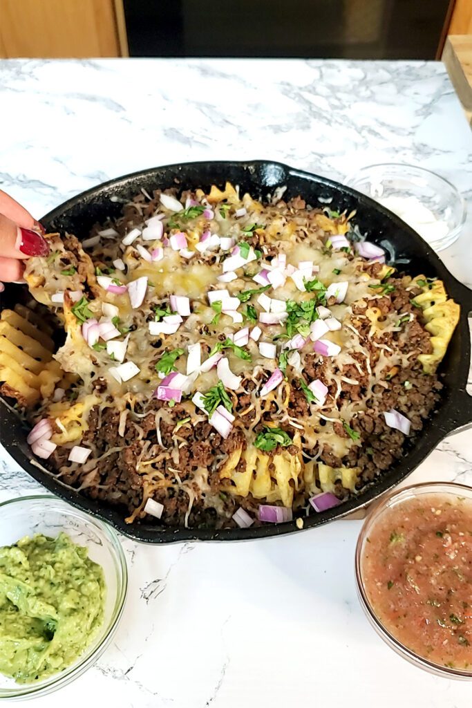 This is an image of Sundays at T's waffle fry nachos topped with seasoned ground beef, a 4 cheese Mexican blend, onions, and fresh cilantro.
