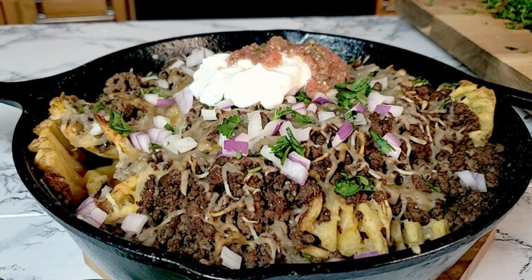 This is an image of Sundays at T's waffle fry nachos topped with seasoned ground beef, a 4 cheese Mexican blend, onions, sour cream, salsa, and fresh cilantro.