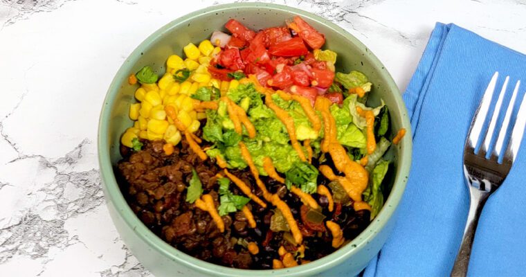 This is an image of the vegan taco bowl with the lentil taco "meat", black beans, lettuce, corn, guacamole, salsa, and chipotle aioli.