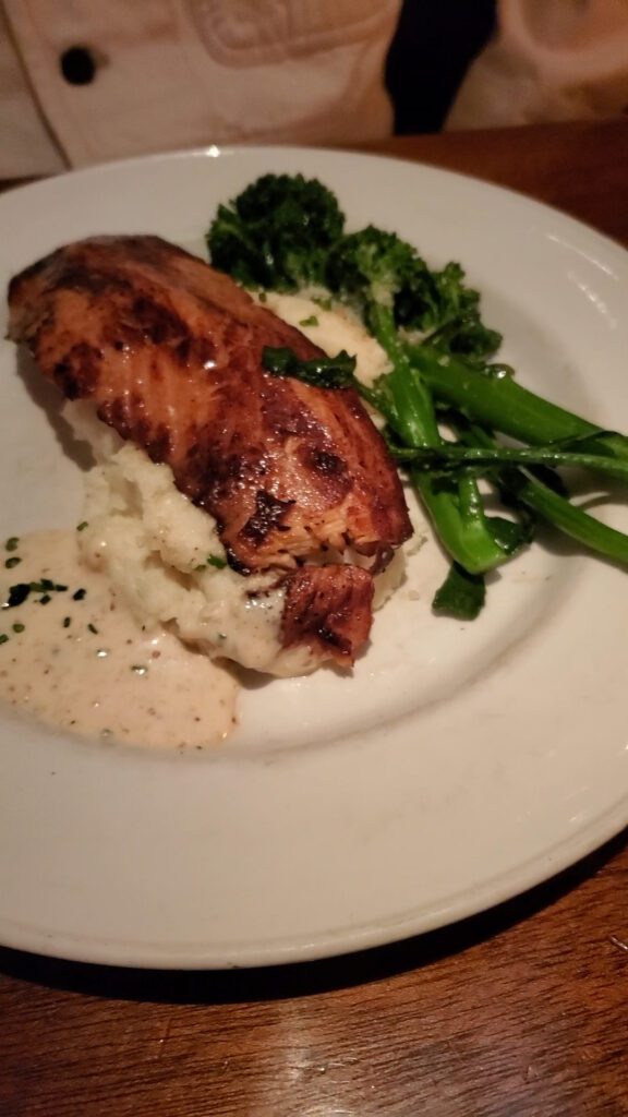 This is an image of the Short Smoked Salmon Filet from Coastal Flats in Fairfax, VA. The salmon is served with broccolini, mashed potatoes and a delicious garlic sauce.