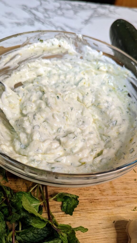 This is an image of the Greek tzatziki freshly mixed with fresh herbs, minced garlic, and grated cucumbers.