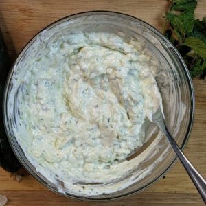 This is an image of the Greek tzatziki freshly mixed with fresh herbs, minced garlic, and grated cucumbers.