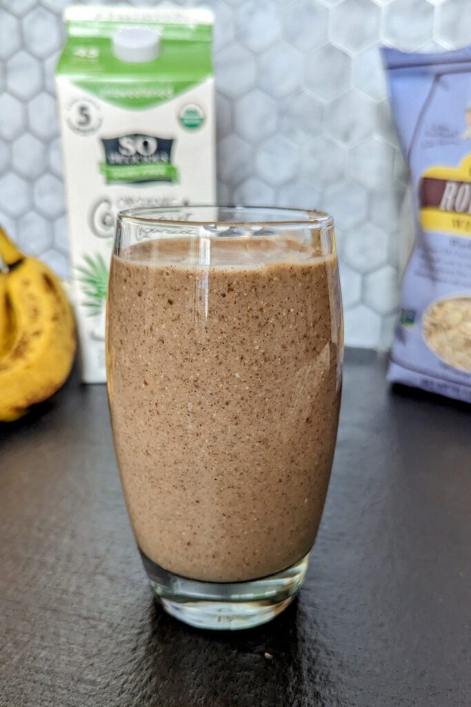 This is an image of the chocolate chia banana smoothie from Sundays at T's. The image is staged with So Delicious Organic Coconut milk, Bob's Red Mill gluten-free rolled oats, and bananas.