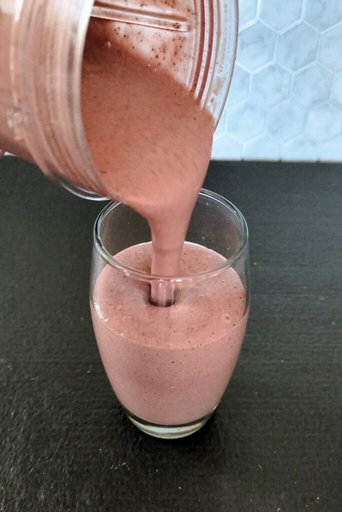 This is an image of the chocolate cherry smoothie from Sundays at T's. The smoothie is being poured into a glass.
