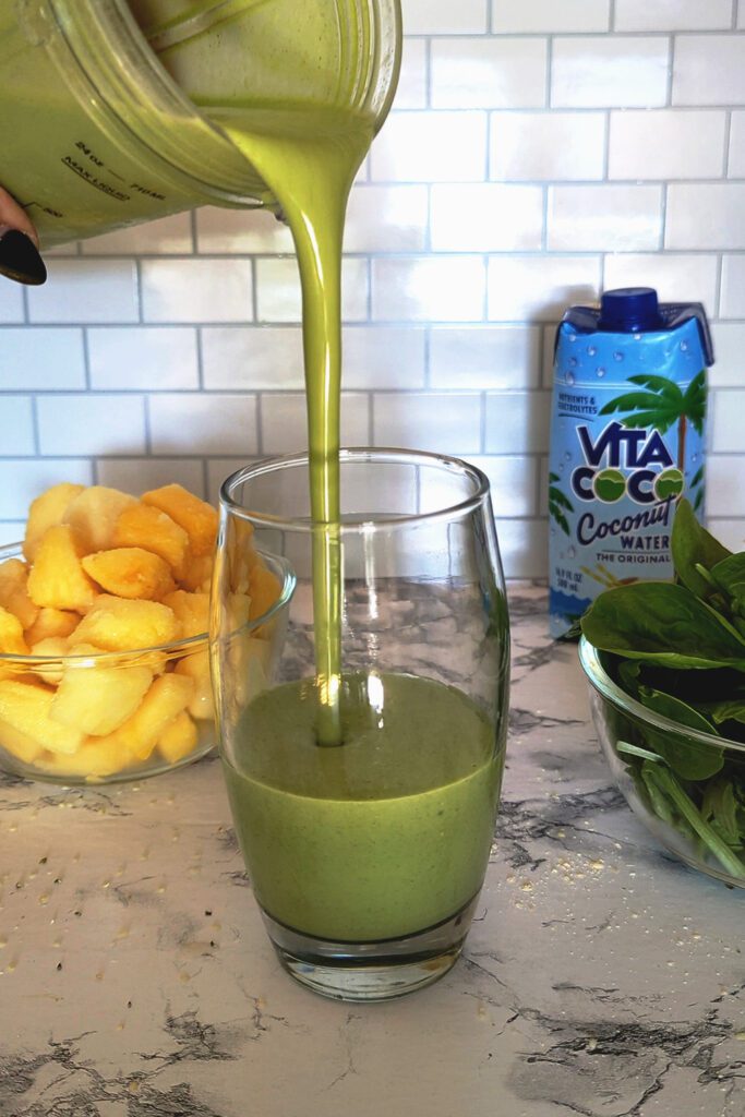 This is an image of the Pineapple Popeye Smoothie from Sundays at T's. The photo is decorated with spinach and pineapples in the background.