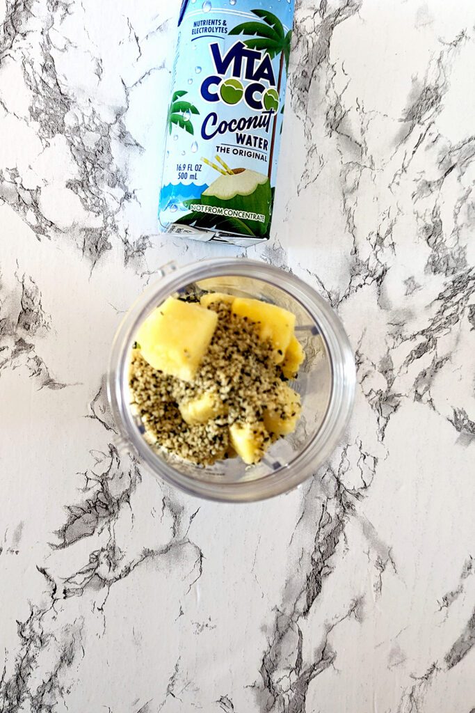 This is an image of the smoothie cup with spinach, pineapple, hemp hearts, and coconut water. These ingredients will make the most amazing Pineapple Popeye Smoothie.