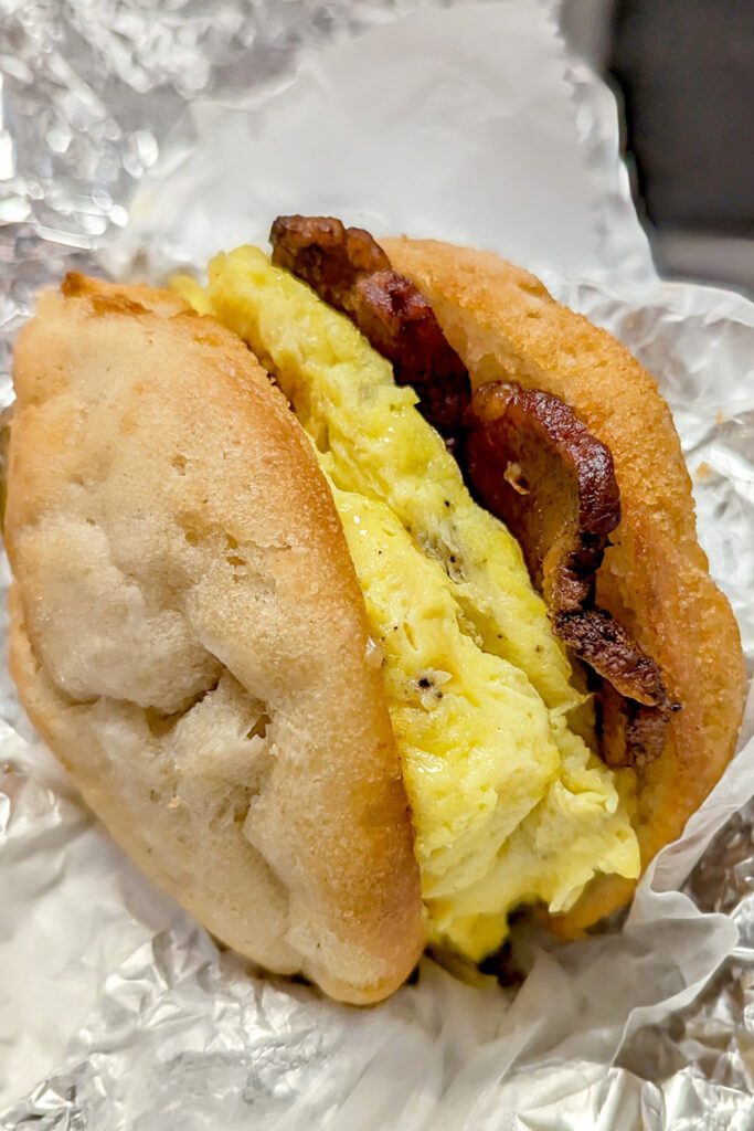 This is an image of Cafe Avalaun's gluten-free Fast Sammy, which is a gluten-free breakfast sandwich with bacon, scrambled eggs, and cheddar cheese. Served on a nut and corn free buttermilk biscuit.