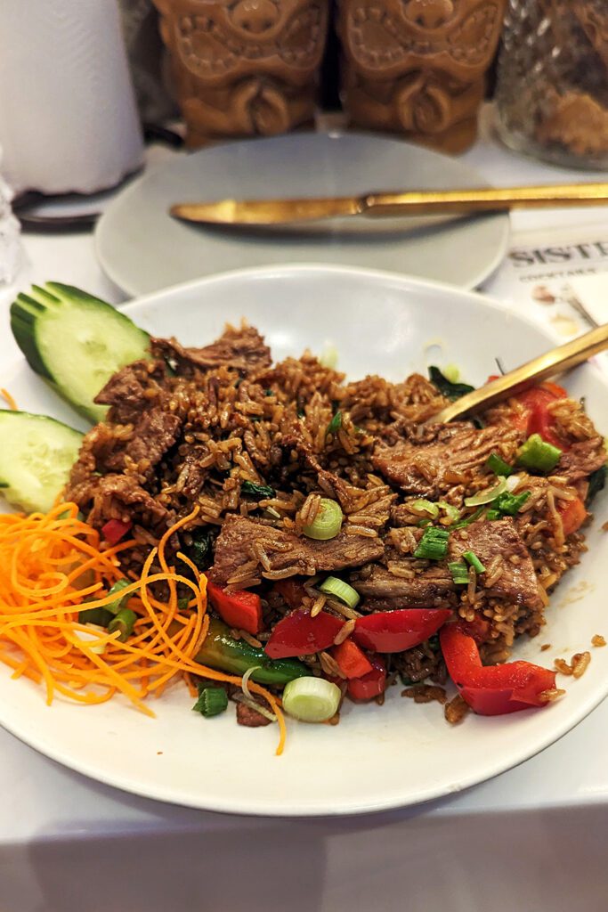This is an image of the Kaprow Fried Rice with Beef from Sisters Thai Alexandria. Garnished with fresh cucumbers and shredded carrots. Tailor your level of spice on any of their menu items.