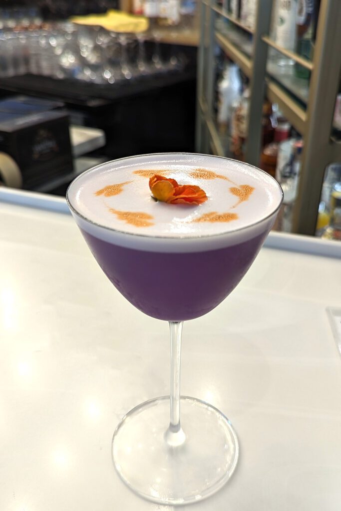 This is an image of the Lily of Sisters, a craft cocktail from Sisters Thai Alexandria. This gin-based cocktail is as delicious as it is beautiful.